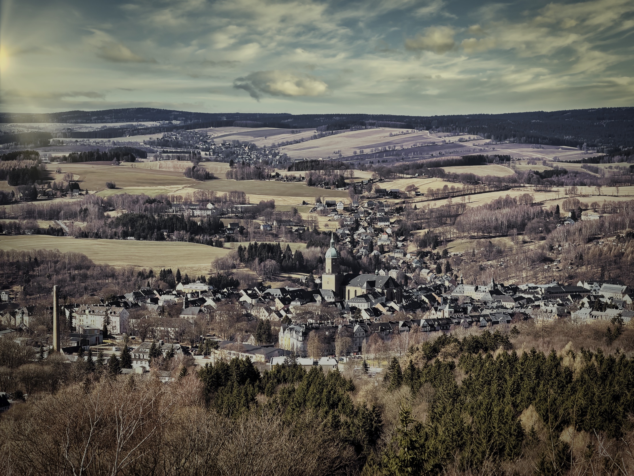 Erzgebirgsstadt mit Kirche und bewaldeten Höhen im Panorama